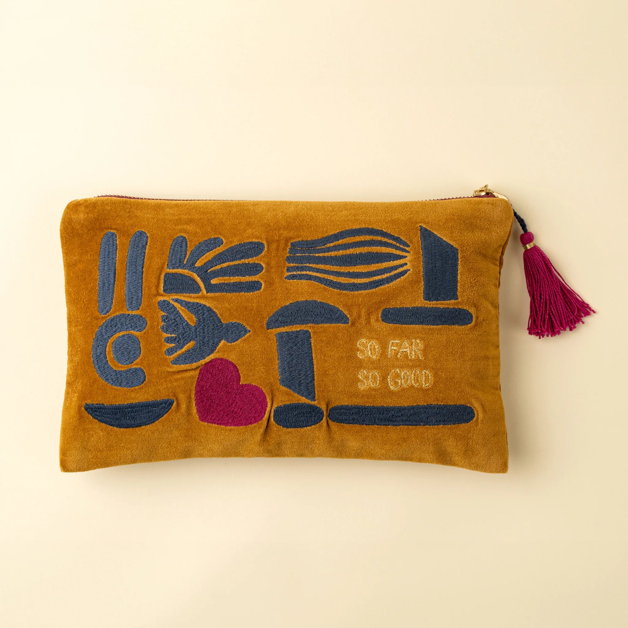 Brown pouch with blue and red designs and 'So Far So Good' text on a beige background