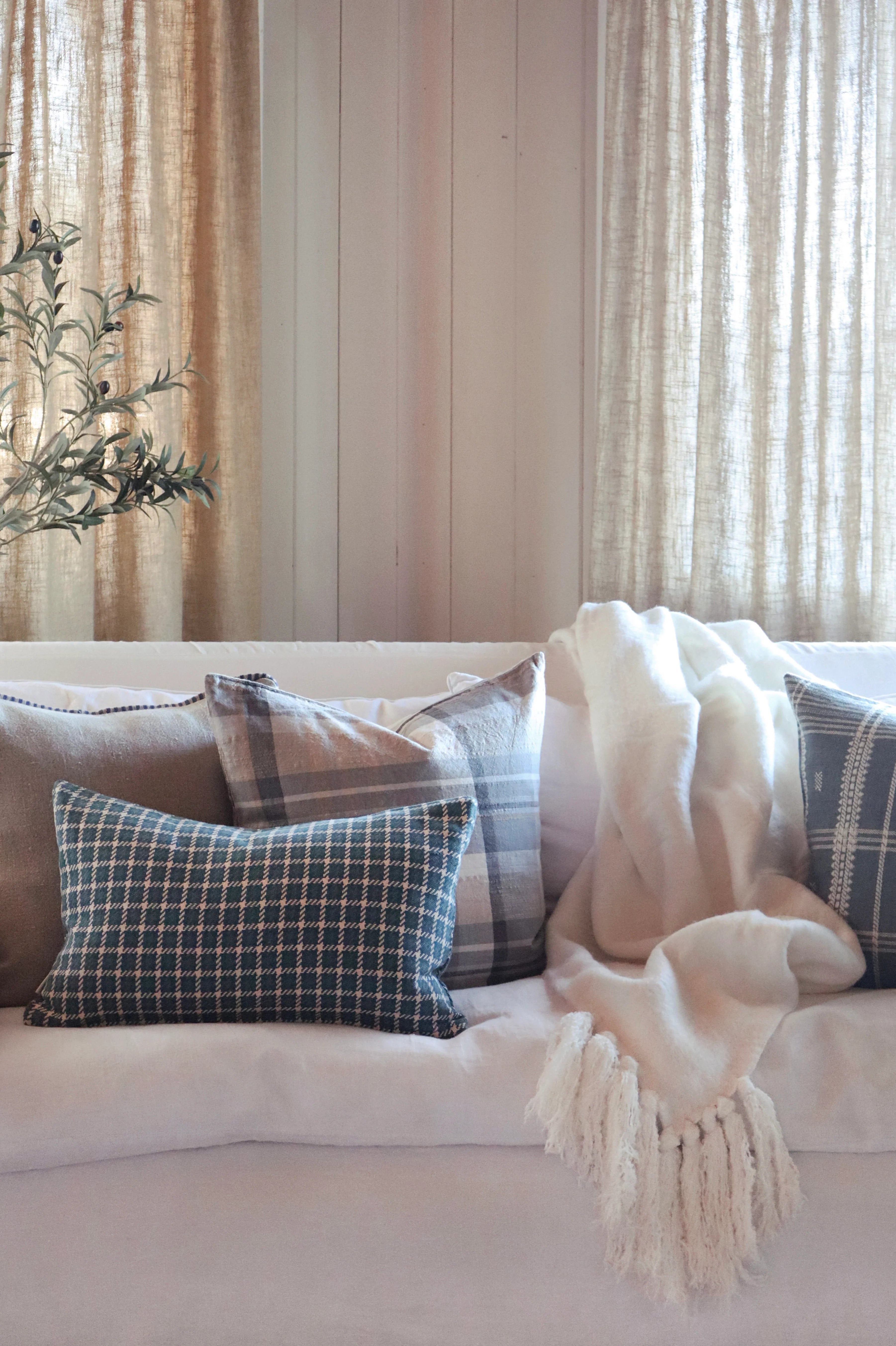 Cozy living room with a beige sofa, plaid pillows, and a white throw blanket.
