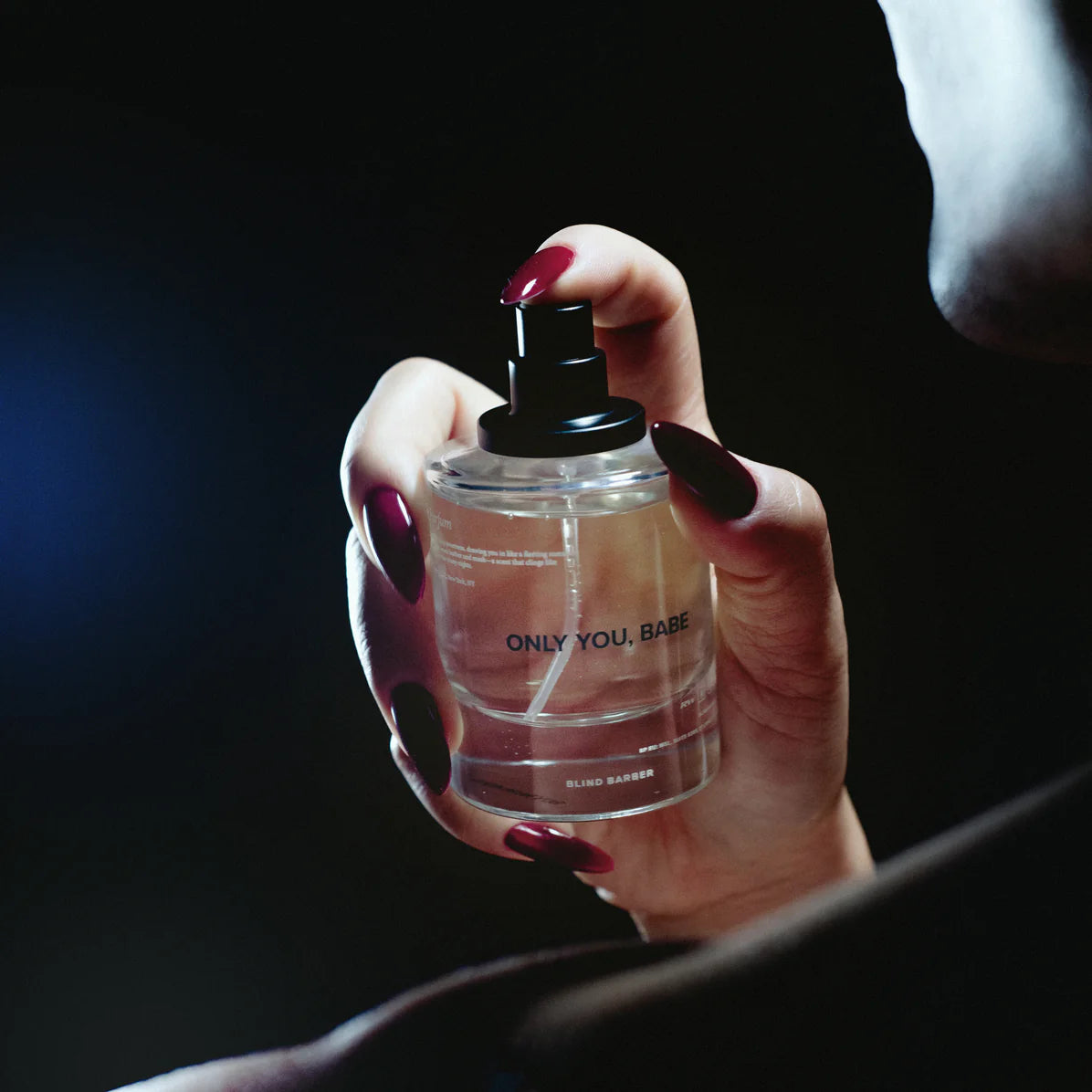 Hand holding a perfume bottle labeled 'ONLY YOU, BABE' against a dark background