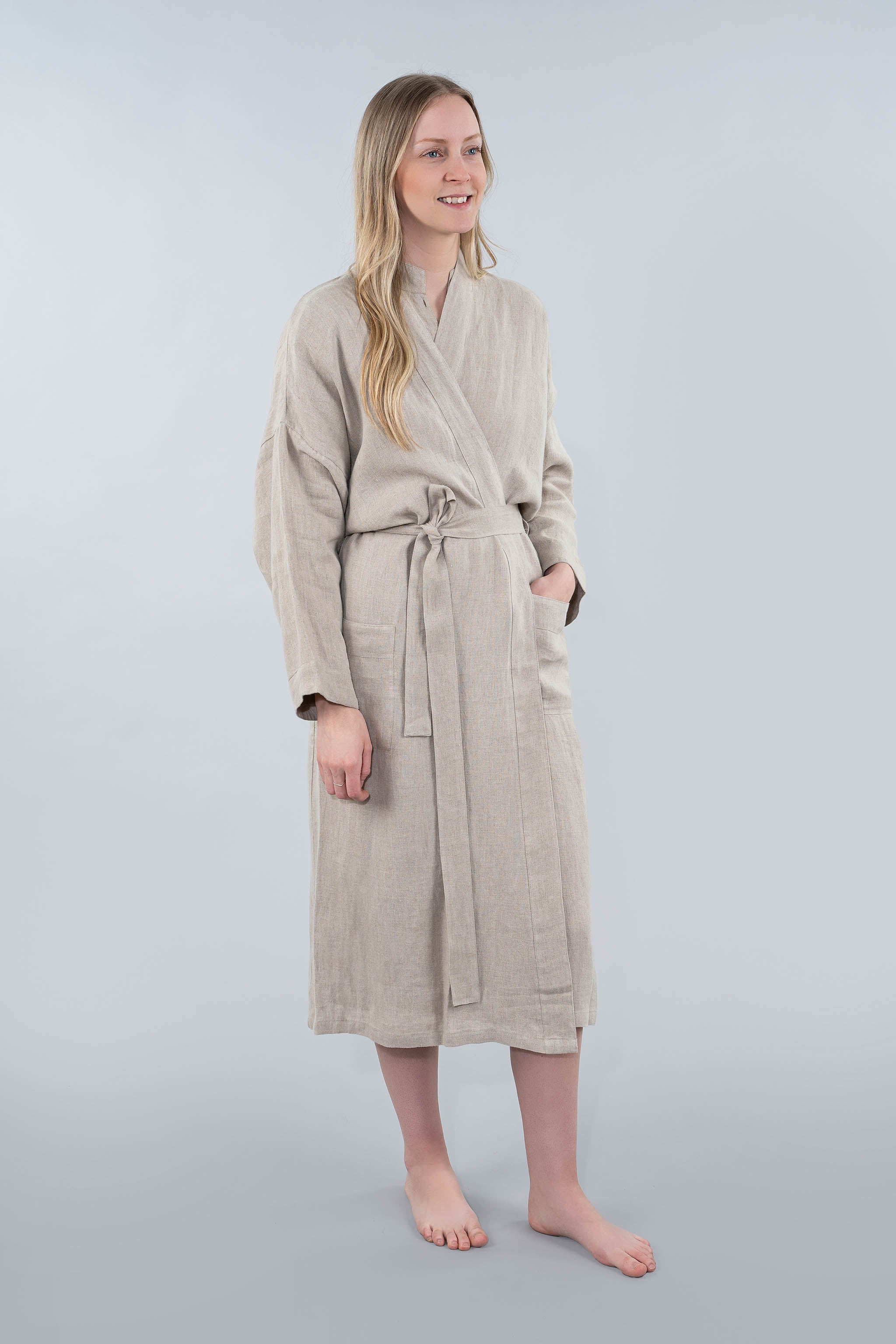 Woman wearing a beige robe against a plain background