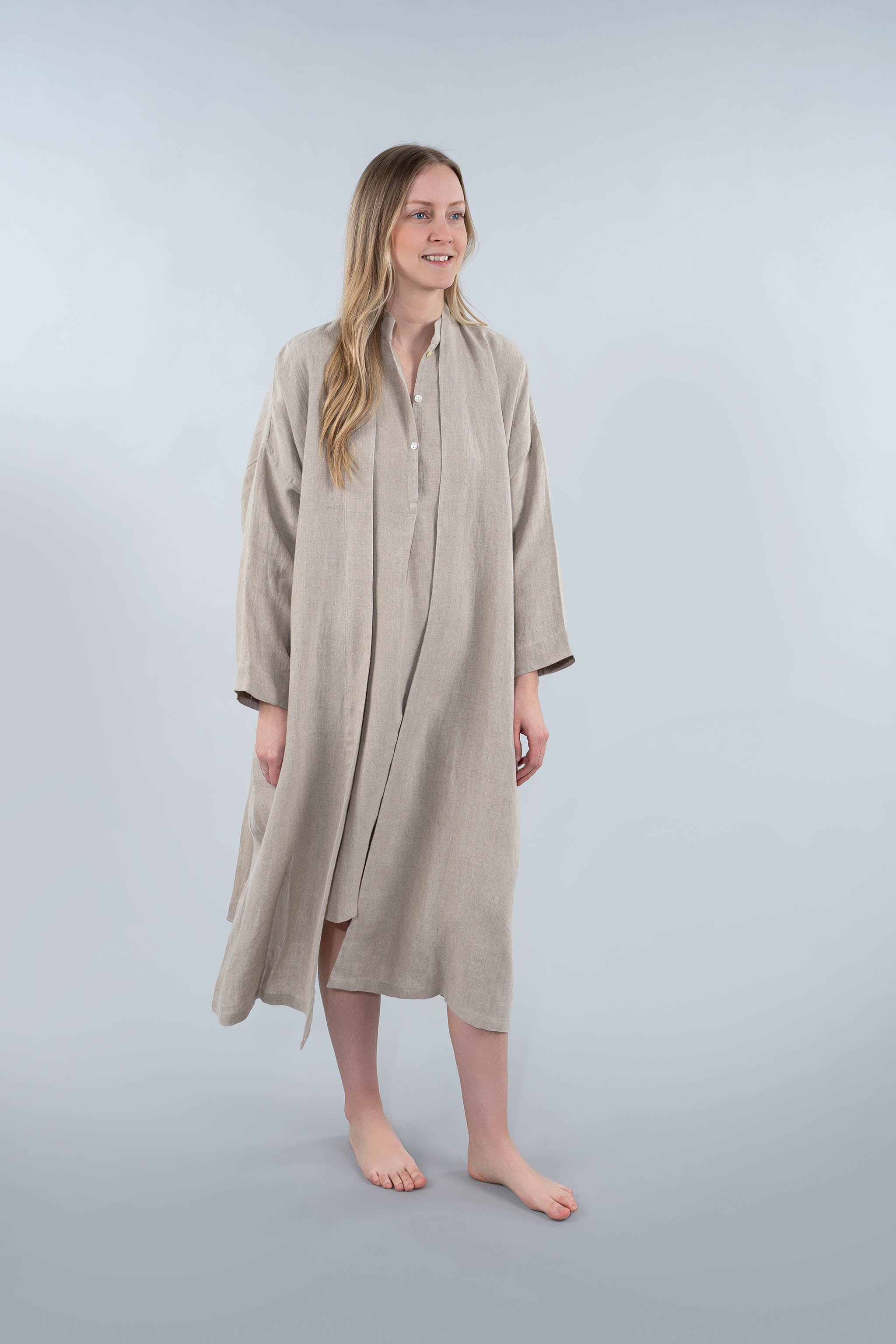 Woman wearing a beige long shirt dress on a plain background