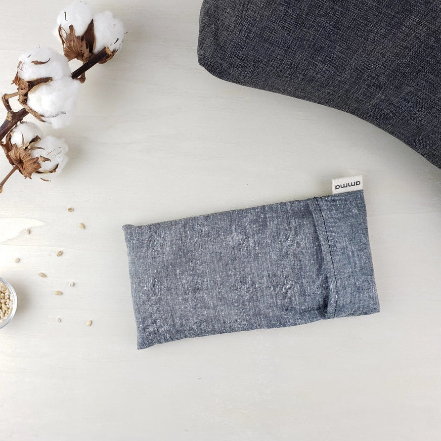 Blue fabric pouch with a brand label on a light surface with cotton and a branch.