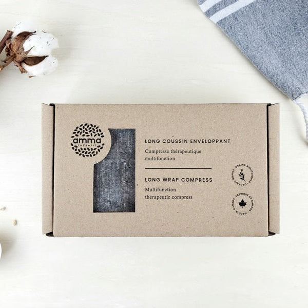 Box of 'amma' long wrap compress on a white background with cotton and towel.