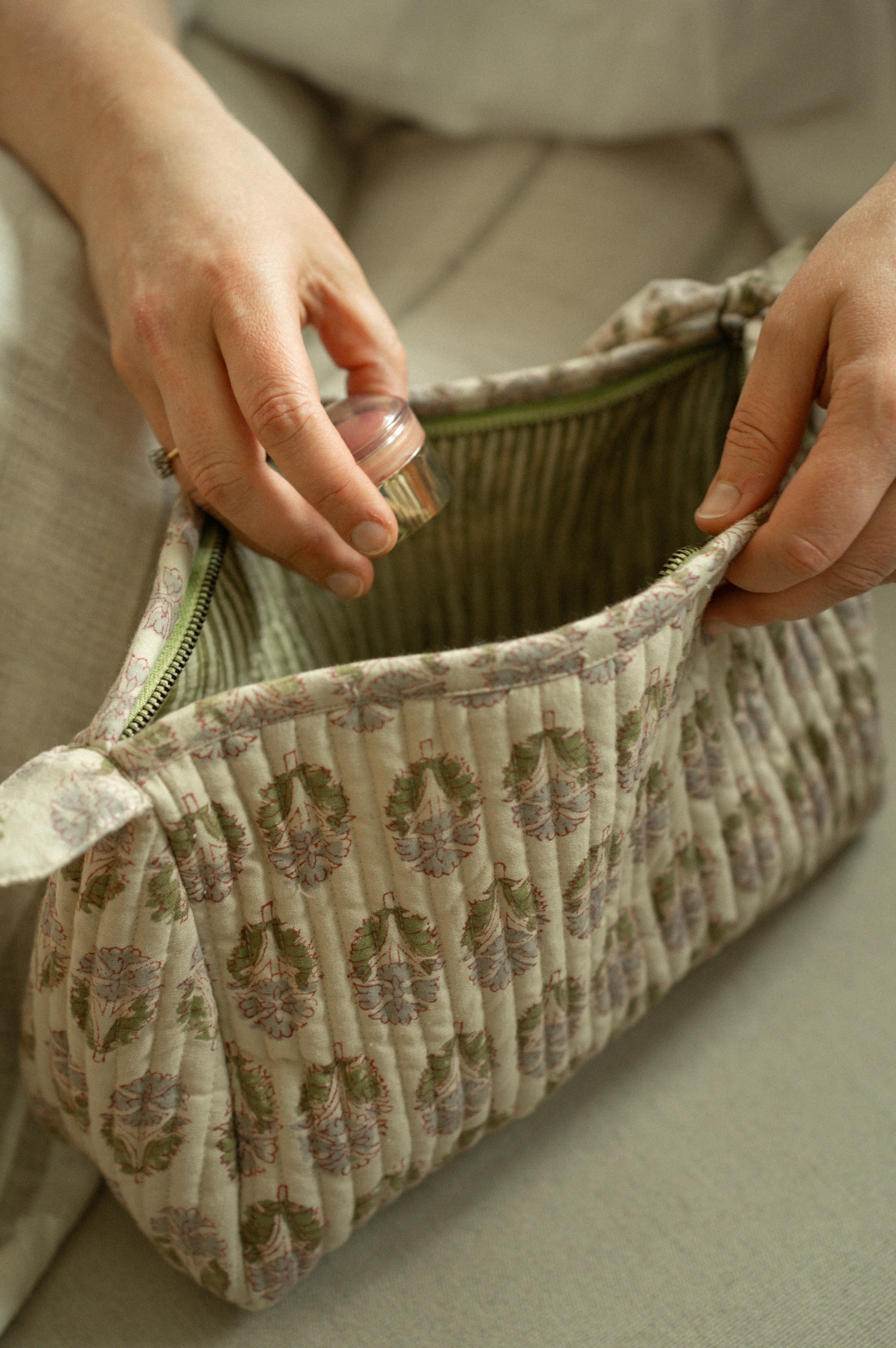 Person opening a patterned fabric bag with a neutral background