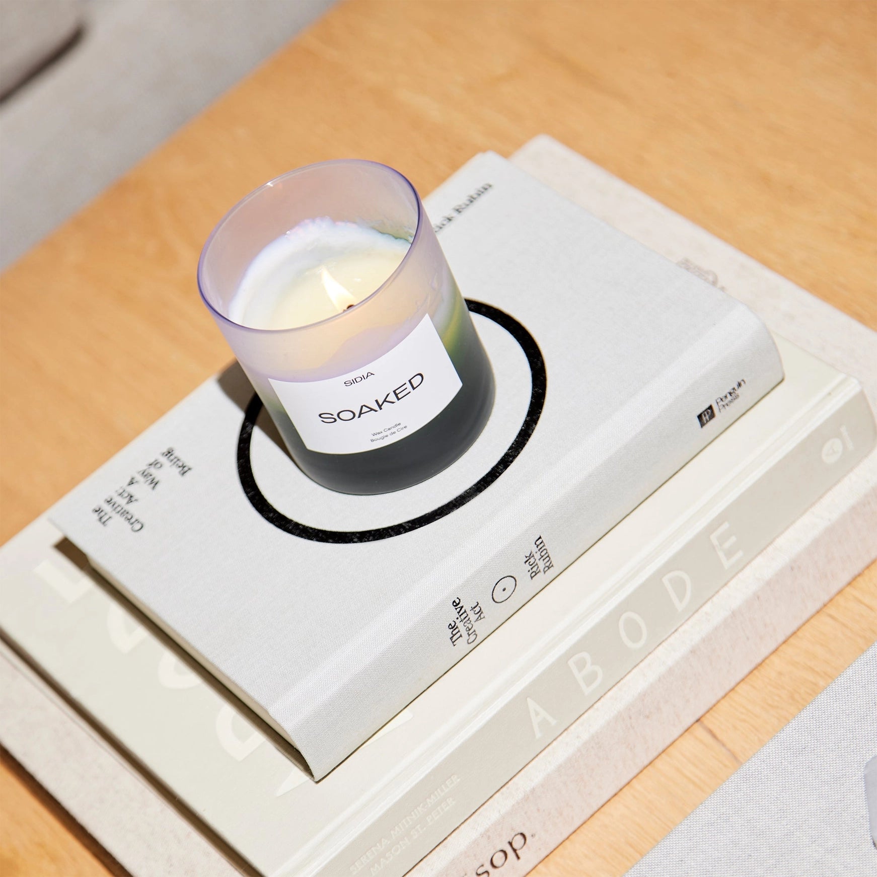 Candle labeled 'Soaked' on top of books with a blurred background