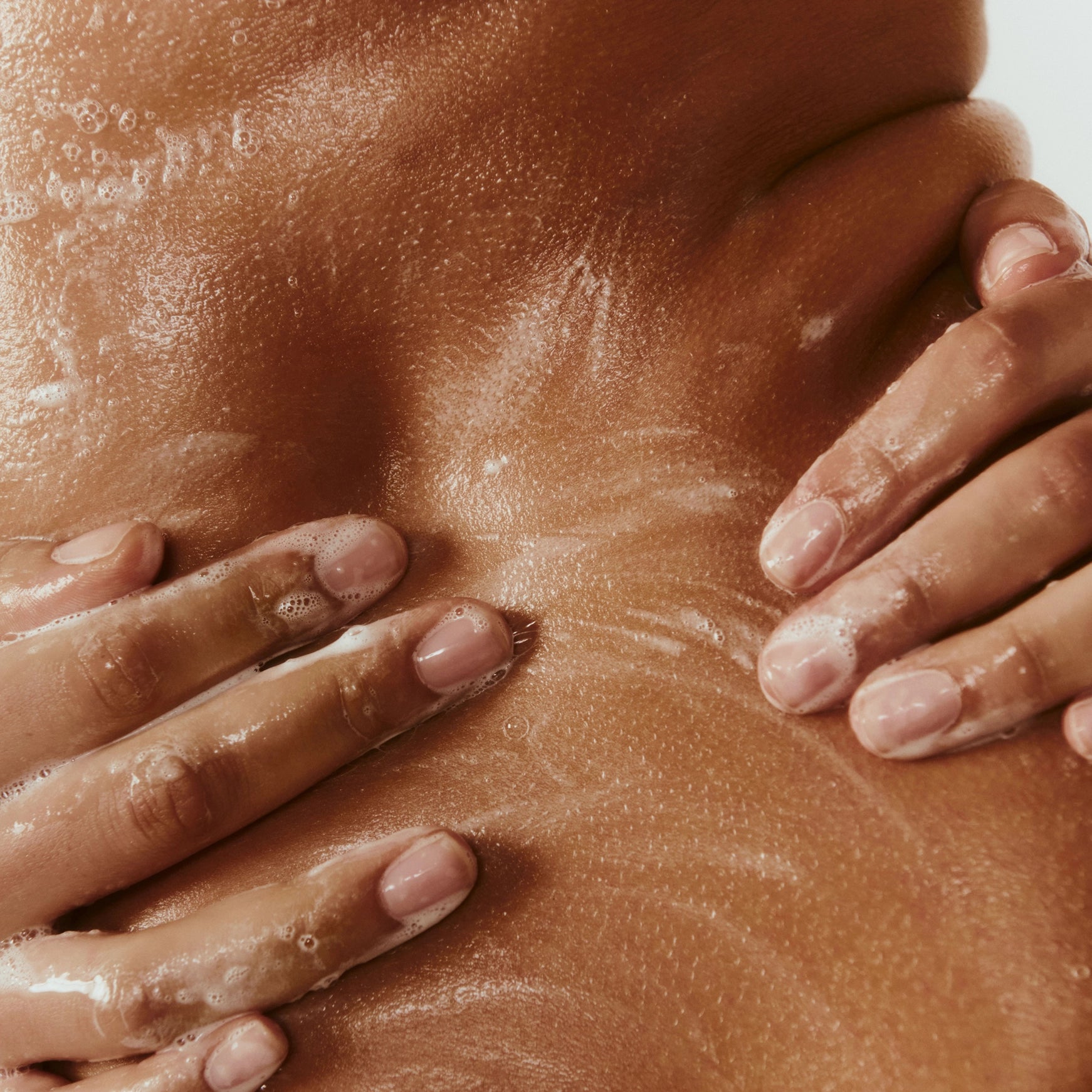 Close-up of a person applying sunscreen to their skin with hands.