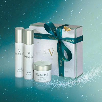Valmont skincare products including bottles and a box on a gradient blue background