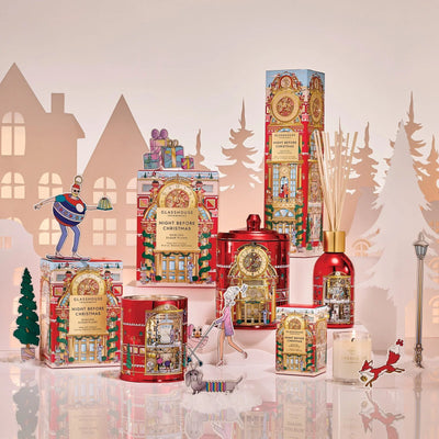Collection des Fêtes Glasshouse Night Before Christmas avec chandelles, diffuseur et boîtes-cadeaux rouges illustrés dans un village d'hiver en papier
