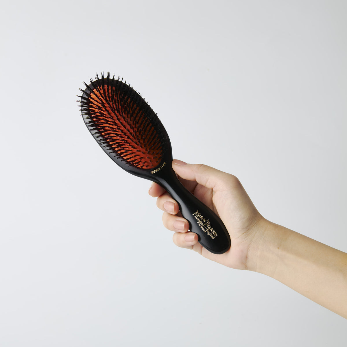 Mason Pearson Handy Sensitive Pure Boar Bristle Hairbrush SB3 in Dark Ruby — held in hand to show the brush size
