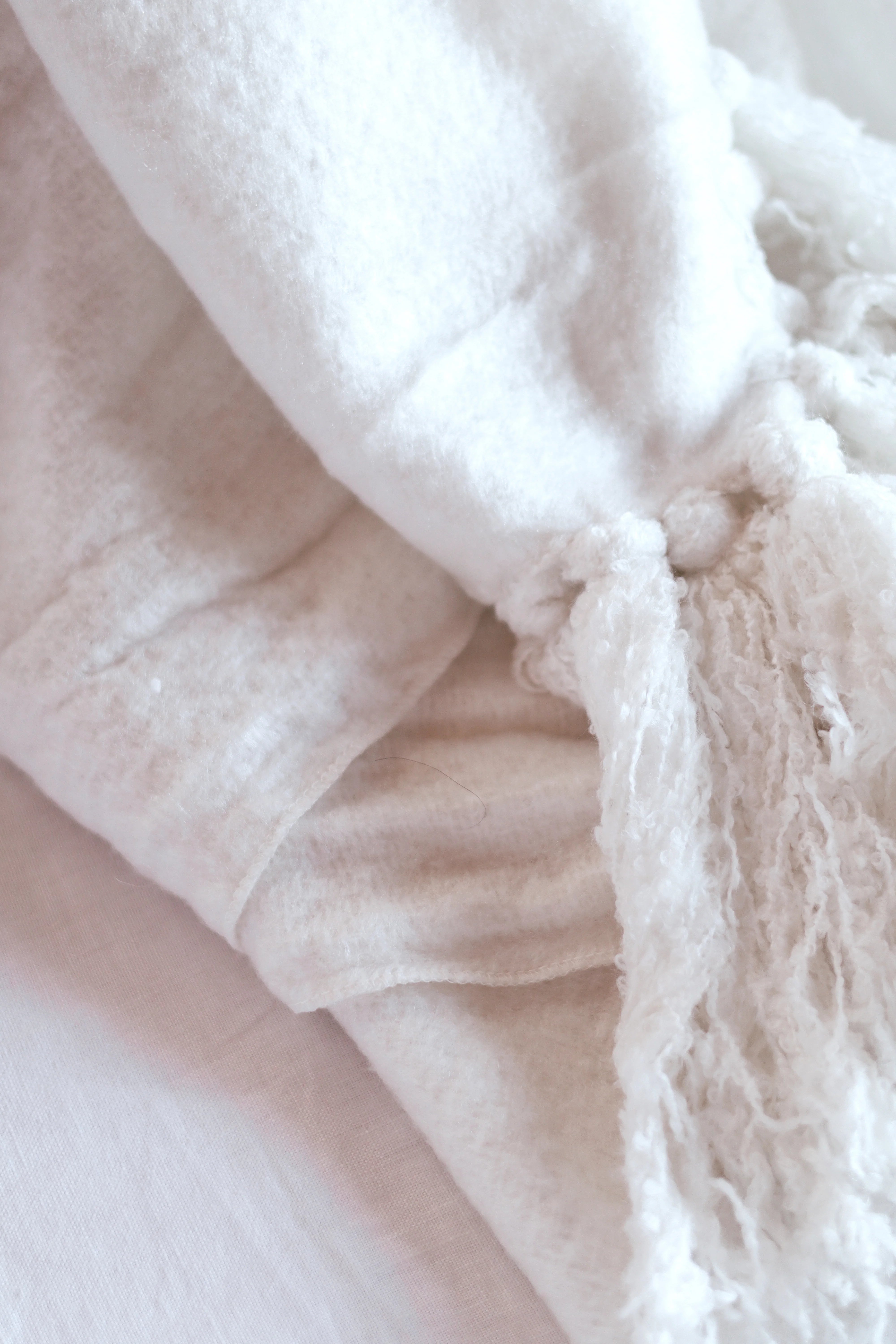 Indaba Alta Wool Blend Throw in a soft neutral colour with oversized hand-knotted tassels