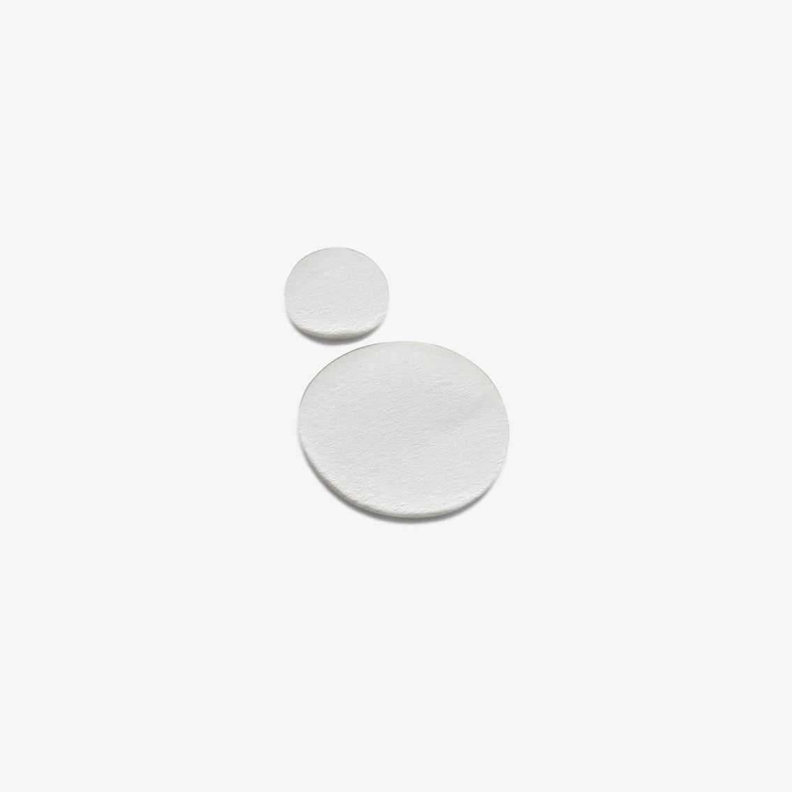 Two white circular earrings on a light beige background