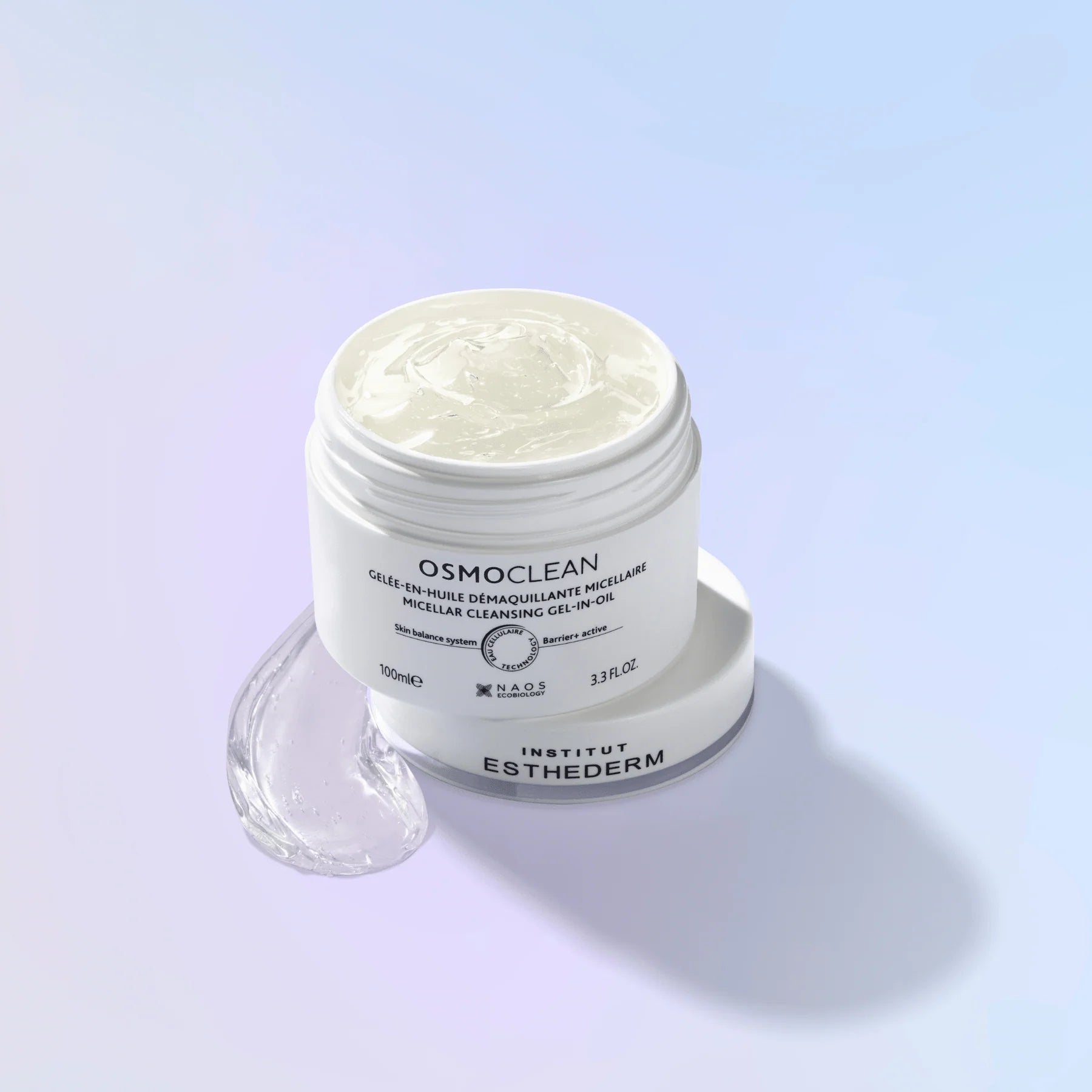 Institut Esthederm Osmoclean Net Clean Clipping Gel in a white jar with its lid placed beside it on a light blue gradient background, with a clear gel swirled in the jar and a small clear gel droplet in the foreground.