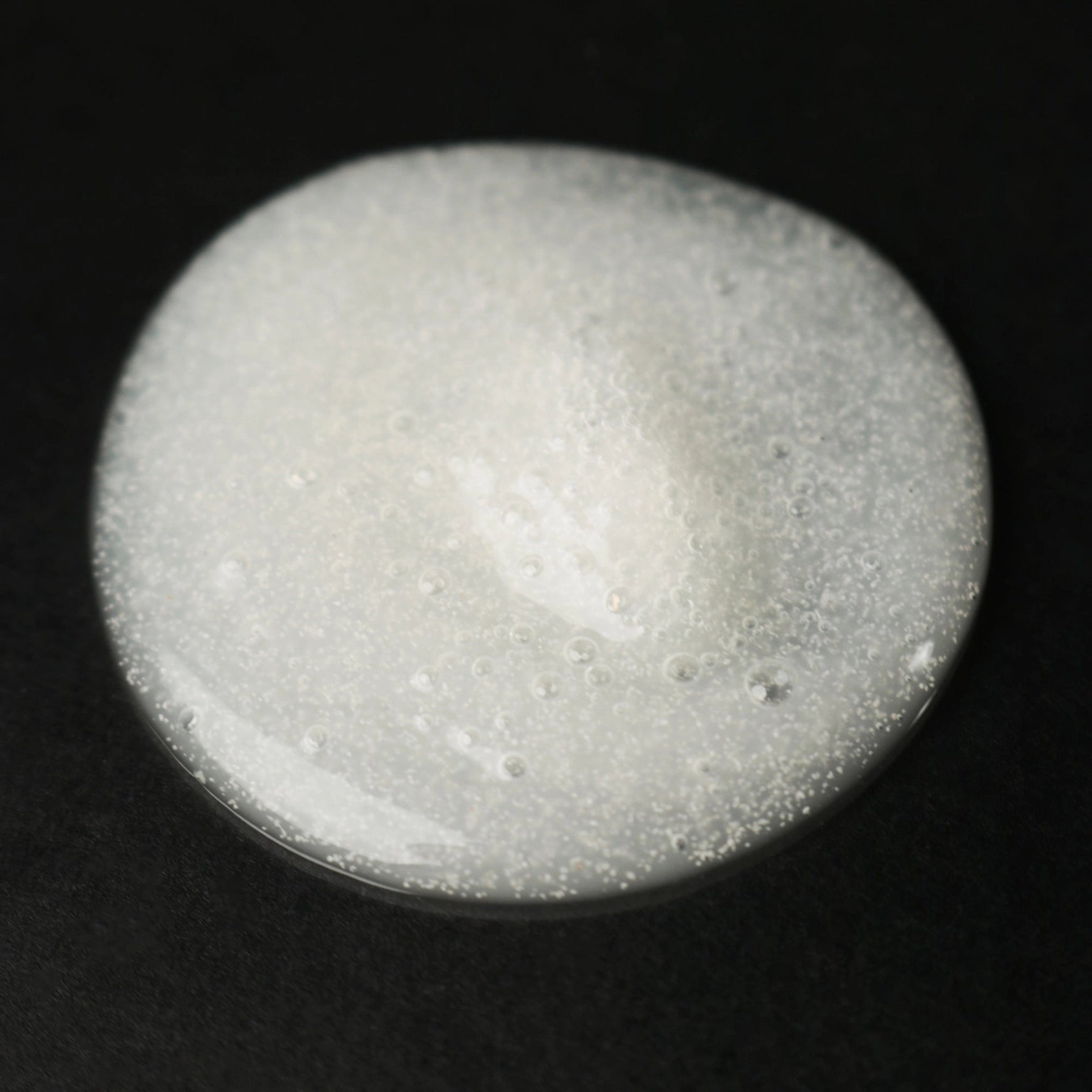 Close-up of a grayish-white circular object on a black background