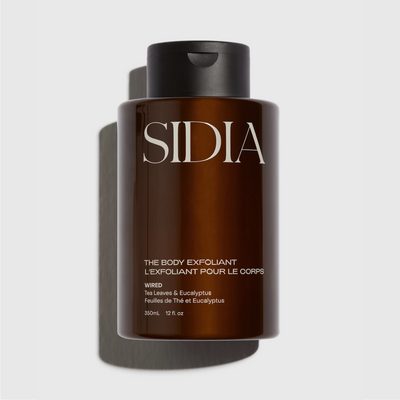 Brown bottle of Sidia body exfoliant on a light gray background