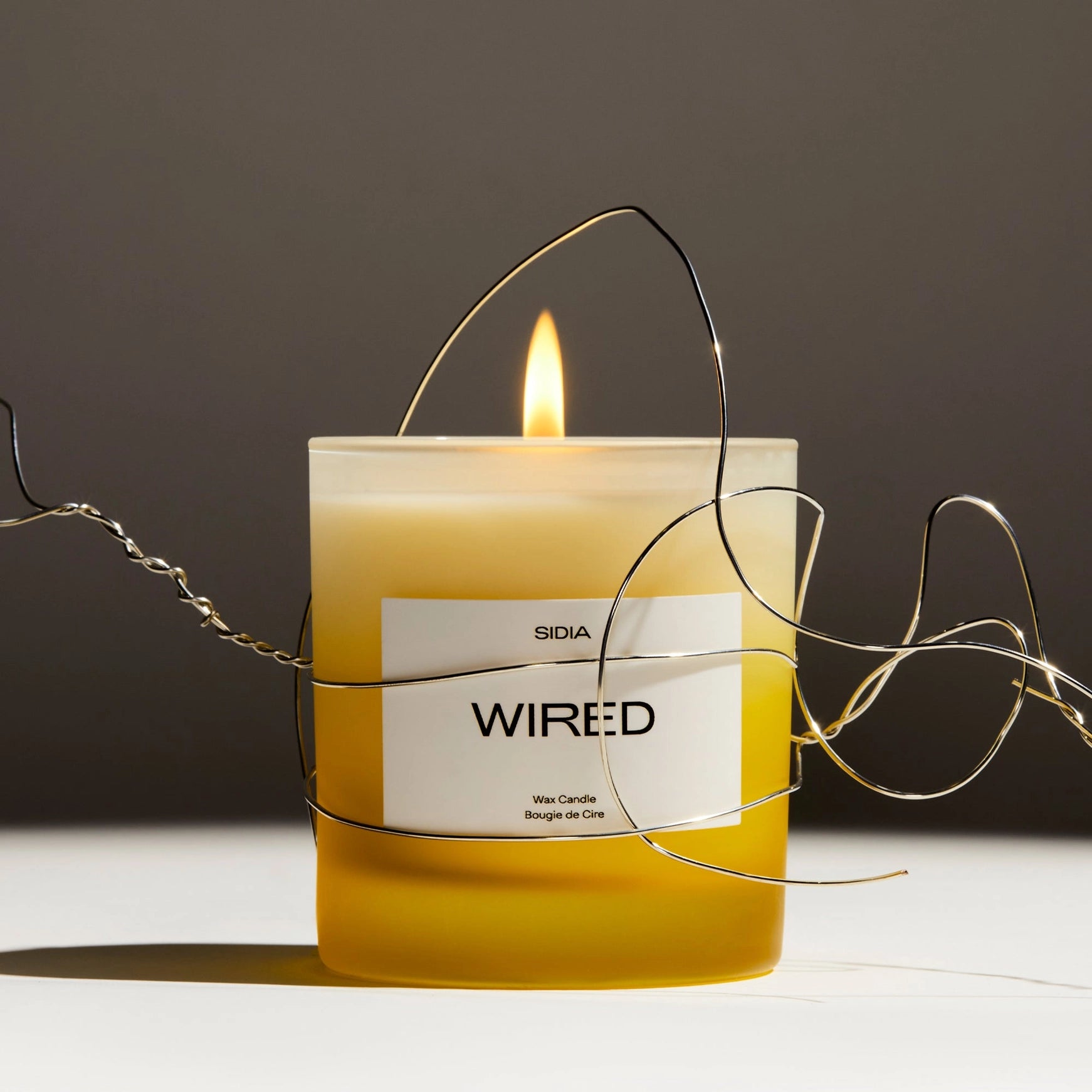 Candle labeled 'WIRED' with a label reading 'SIDIA' on a dark background