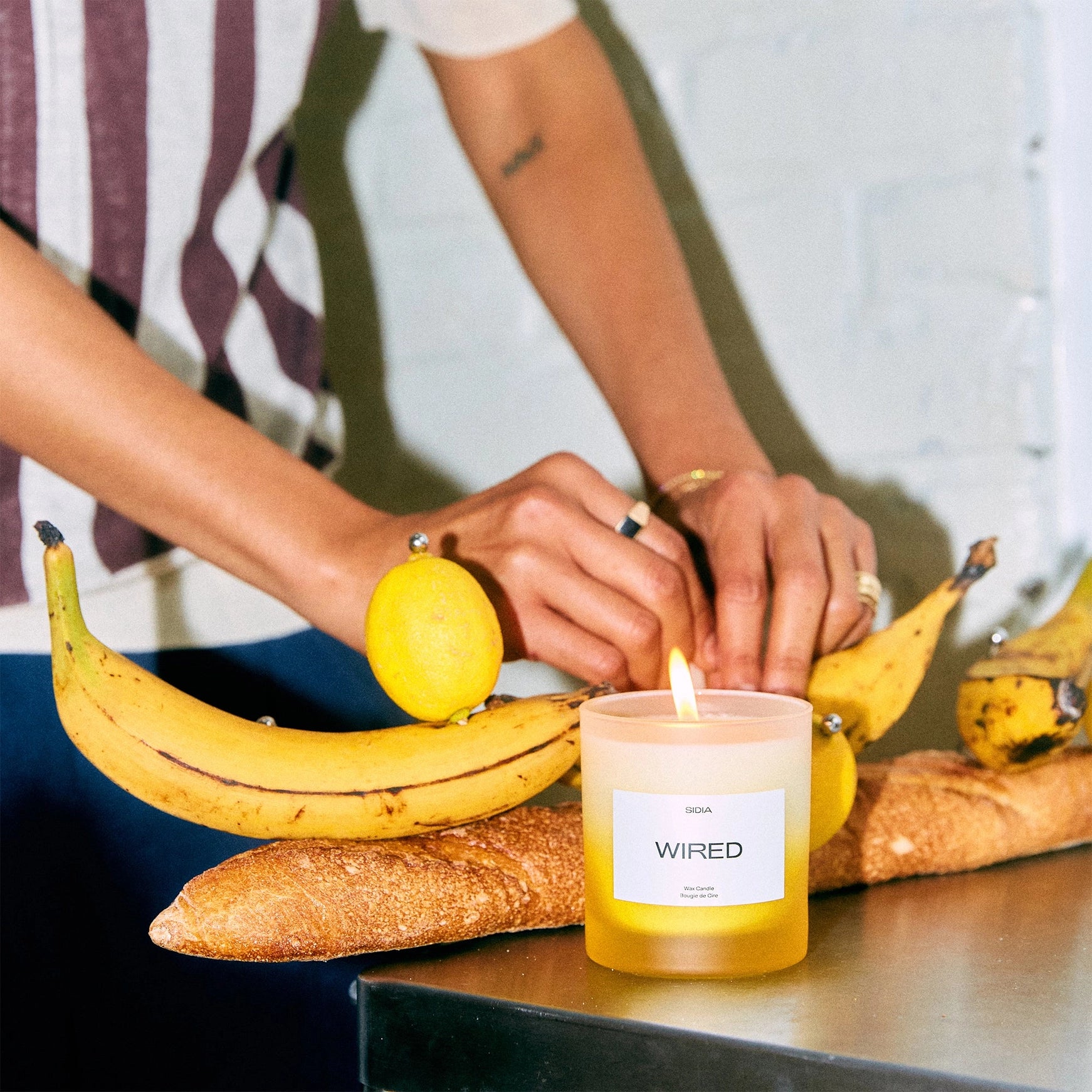 Candle labeled 'WIRED' with bananas and bread on a table