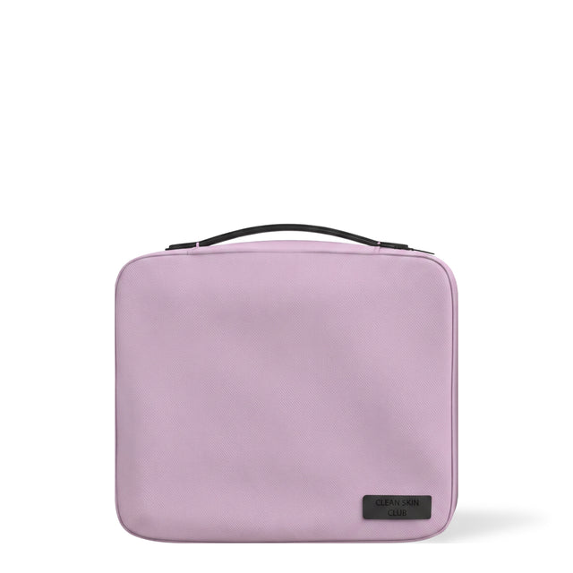 Trousse de voyage The Bag Clean Skin Club, lilas, avec poignée noire, sur fond blanc