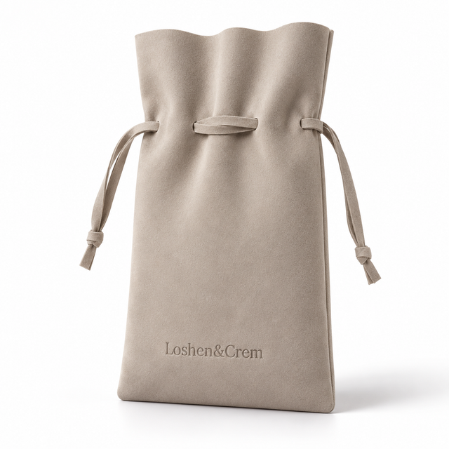 La Pochette Loshen in taupe faux suede, standing in a three-quarter studio view on white.