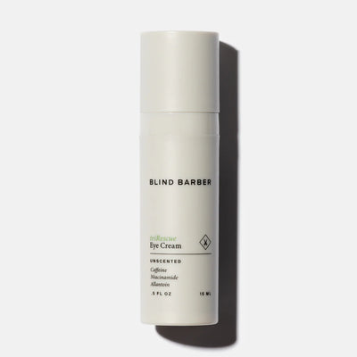 White eye cream bottle with 'Blind Barber' branding on a light gray background